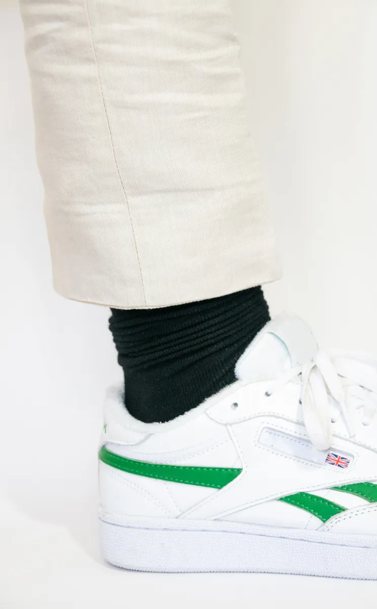 Zwarte Hipperboo bamboesok in een witte sneaker onder een beige broek